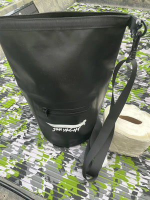 Black 5L Jon Yacht dry bag with front zipper pocket and shoulder strap, next to a roll of toilet paper.