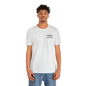Man in a light gray unisex jersey tee with "EXPERIENCE OVER EXTRAVAGANCE" text on the left chest.