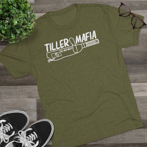 Olive green tri-blend "Tiller Mafia" graphic tee with a boat tiller design, black sneakers, and glasses.