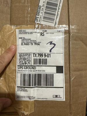 Hand holding a UPS shipping label on a cardboard box