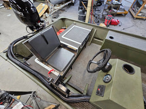 Green boat interior with a black flip-up stowable JumpSeat, steering wheel, and textured deck.