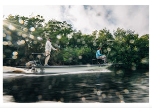 Newport NT600 6hp electric outboard on a white jon boat with two people, cruising through mangroves.