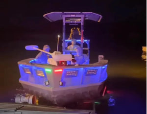 Small boat with blue, red, and green LED lights illuminating its exterior and interior figures.