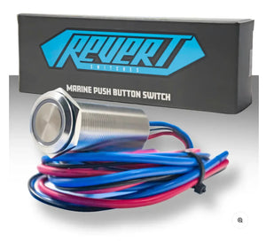 Silver 22mm Plashlights REVERT marine push button switch with blue and red wires, in front of its black box.