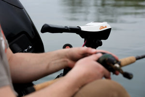White and black Pro Controll L-type 50lb thrust trolling motor mounted on a boat, with a person holding a fishing rod.