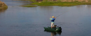 Man fly fishing from a compact Hunter Green Sea Eagle 285 frameless inflatable pontoon boat on a calm lake.