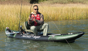 Man fishing from a green and black Sea Eagle FastTrack Angler inflatable kayak with two fishing rods.