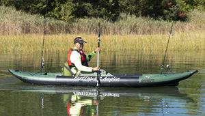 Green Sea Eagle 385fta FastTrack Angler inflatable kayak with a paddler and fishing rods on calm water.