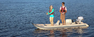 Two people fishing from a tan Sea Eagle 437ps PaddleSki inflatable catamaran with a Honda motor.
