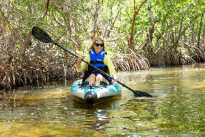 Woman in a blue life vest paddling a light blue inflatable kayak with a black AB50 paddle.