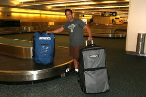Man with a large blue Sea Eagle backpack on a luggage carousel and a gray rolling bag.