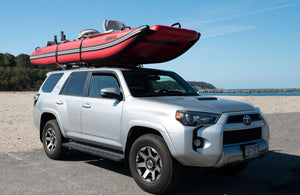 Red Sea Eagle FastCat12 inflatable catamaran boat on a silver SUV roof rack at the beach.