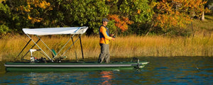 Man fishing from a green Sea Eagle FishSkiff 16 inflatable boat with a white canopy.