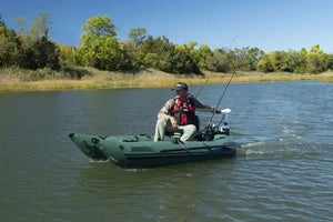 Man in green inflatable fishing boat with white electric motor and fishing rods.