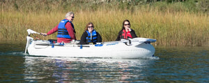White Sea Eagle 9 inflatable boat with three people wearing life vests, powered by an electric motor.
