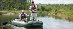 Two men fishing from a green Sea Eagle Stealth Stalker 10 inflatable boat on a calm river.
