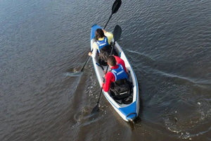 Two people in a blue and white inflatable kayak with black Tall Back Kayak Seats and paddles.
