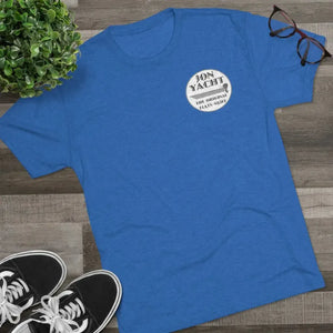 Blue "Jon Yacht The Original Flats Skiff" graphic tee, black sneakers, plant, and glasses on wood.