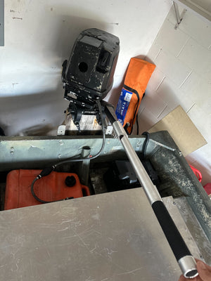Silver aluminum X-LONG tiller extension handle with black grip on an outboard motor in a boat.