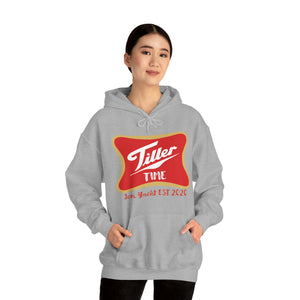Woman wearing a gray Tiller Time hooded sweatshirt with a red and gold graphic, kangaroo pocket.
