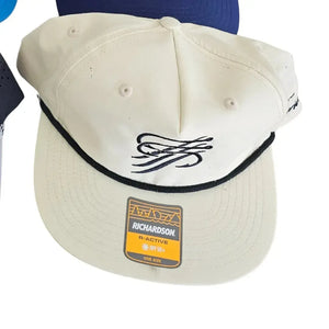 Cream Richardson R-Active hat with black rope trim and embroidered fishing hook logo.