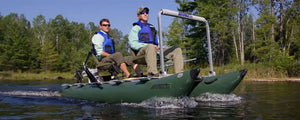 Two men in life vests on a dark hunter green Sea Eagle 375fc FoldCat inflatable fishing boat on a lake.