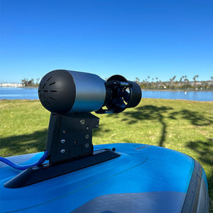 Blue vehicle with a mounted device against a clear blue sky and grassy area.
