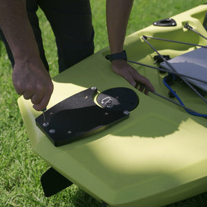 Person adjusting a device on a green kayak outdoors