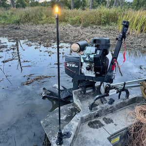 Illuminated Max It Out LEDs Premier Universal LED Stern Light standing upright on the deck of a boat in a marsh setting.