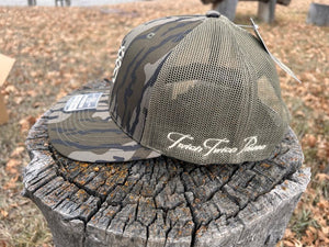 Camouflage baseball cap with 'Twich Twich Pause' branding on a wooden stump.