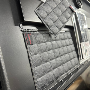 Black textured Magnalure Pad with quilted design, red logo tag, shown attached to a dark surface.