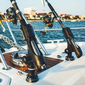 Two black Railblaza StarPort bases securing fishing rods on a boat deck with water in the background.