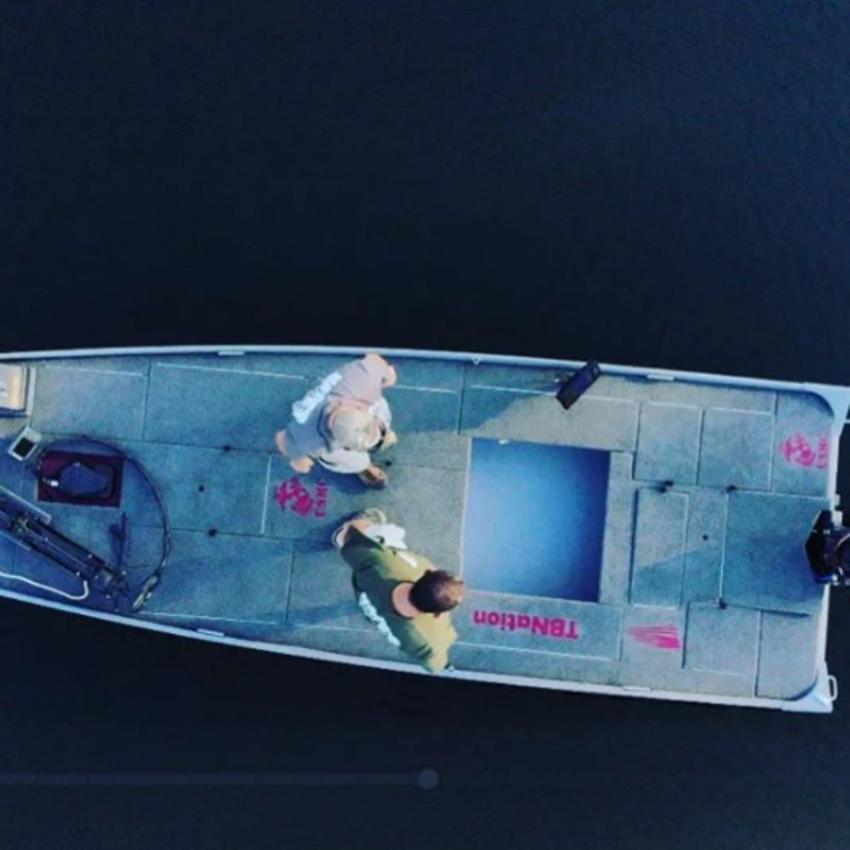 Aerial view of a gray jon boat with two men, featuring premium gray cut pile marine carpet.