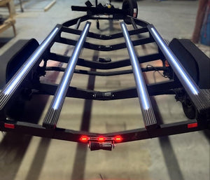 Black boat trailer with four illuminated Gatorbak XP synthetic bunk covers and red tail lights.