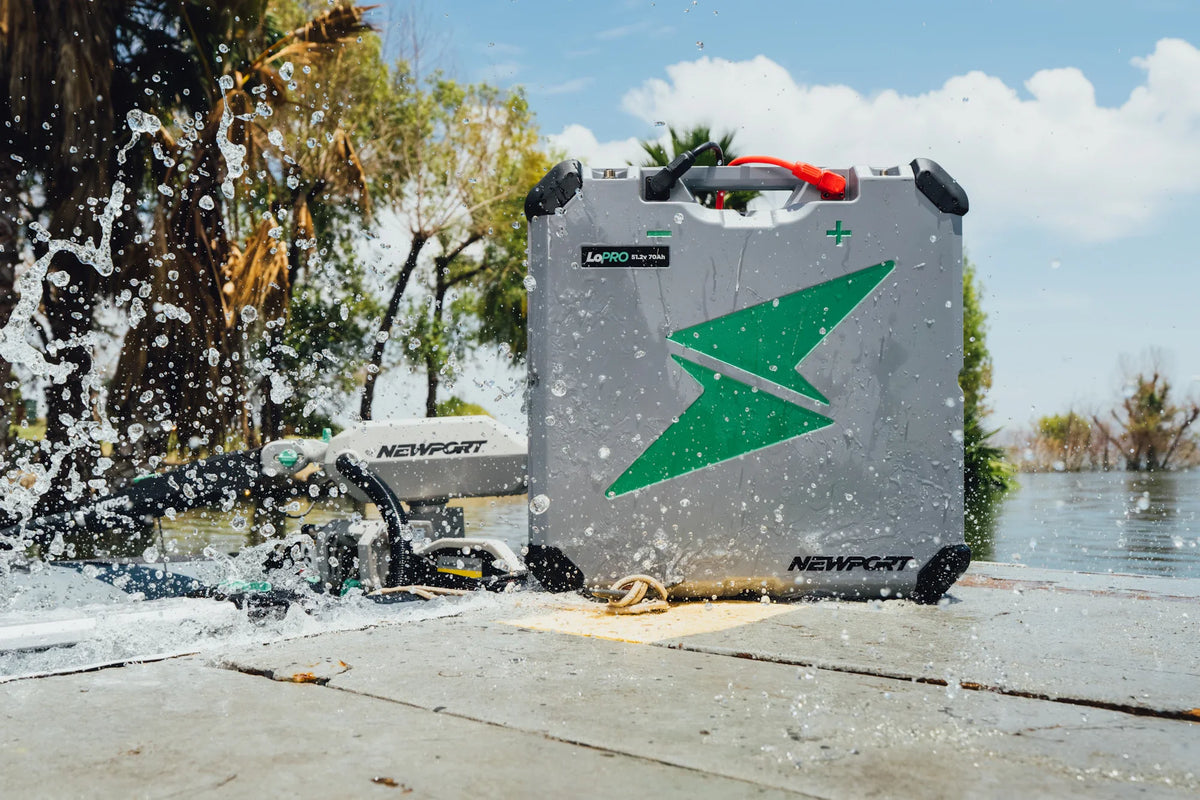 Gray Newport LoPRO 48V 70Ah lithium battery with green lightning bolt logo, being splashed with water.