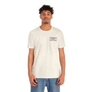 Man in a cream "American Dreamer" t-shirt with "EXPERIENCE OVER EXTRAVAGANCE" text on the left chest.