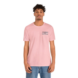 Man in a light pink American Dreamer t-shirt with "EXPERIENCE OVER EXTRAVAGANCE" text.