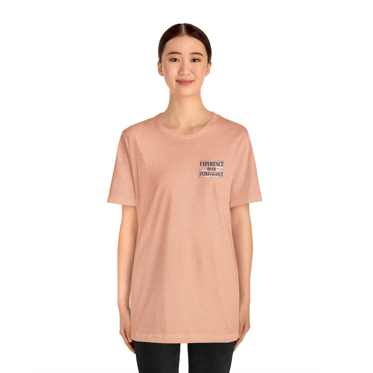 Woman wearing a peach "Experience Over Extravagance" unisex short sleeve tee.