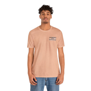 Man wearing a peach "American Dreamer" t-shirt with "EXPERIENCE OVER EXTRAVAGANCE" text on the left chest.
