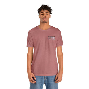 Man in a heather mauve "American Dreamer" t-shirt with "EXPERIENCE OVER EXTRAVAGANCE" text on the chest.