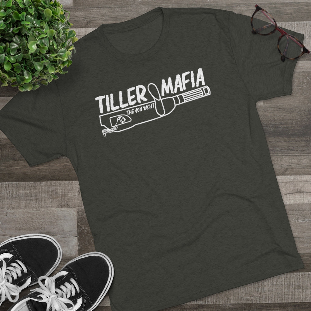 Dark gray tri-blend "Tiller Mafia" graphic tee with white design, black sneakers, plant, and glasses.