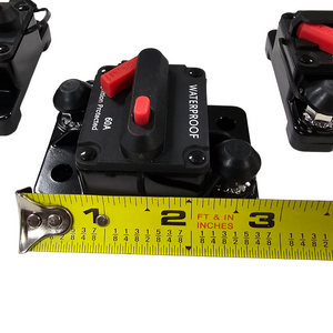 Black 60A waterproof circuit breaker with red reset button, shown with a tape measure for size.