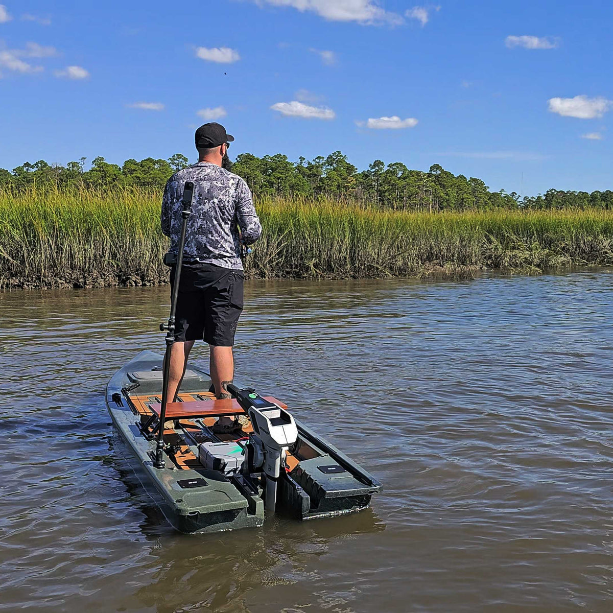Angler standing in an olive Crescent Cres-Craft fishing skiff with a motor, on a calm river.