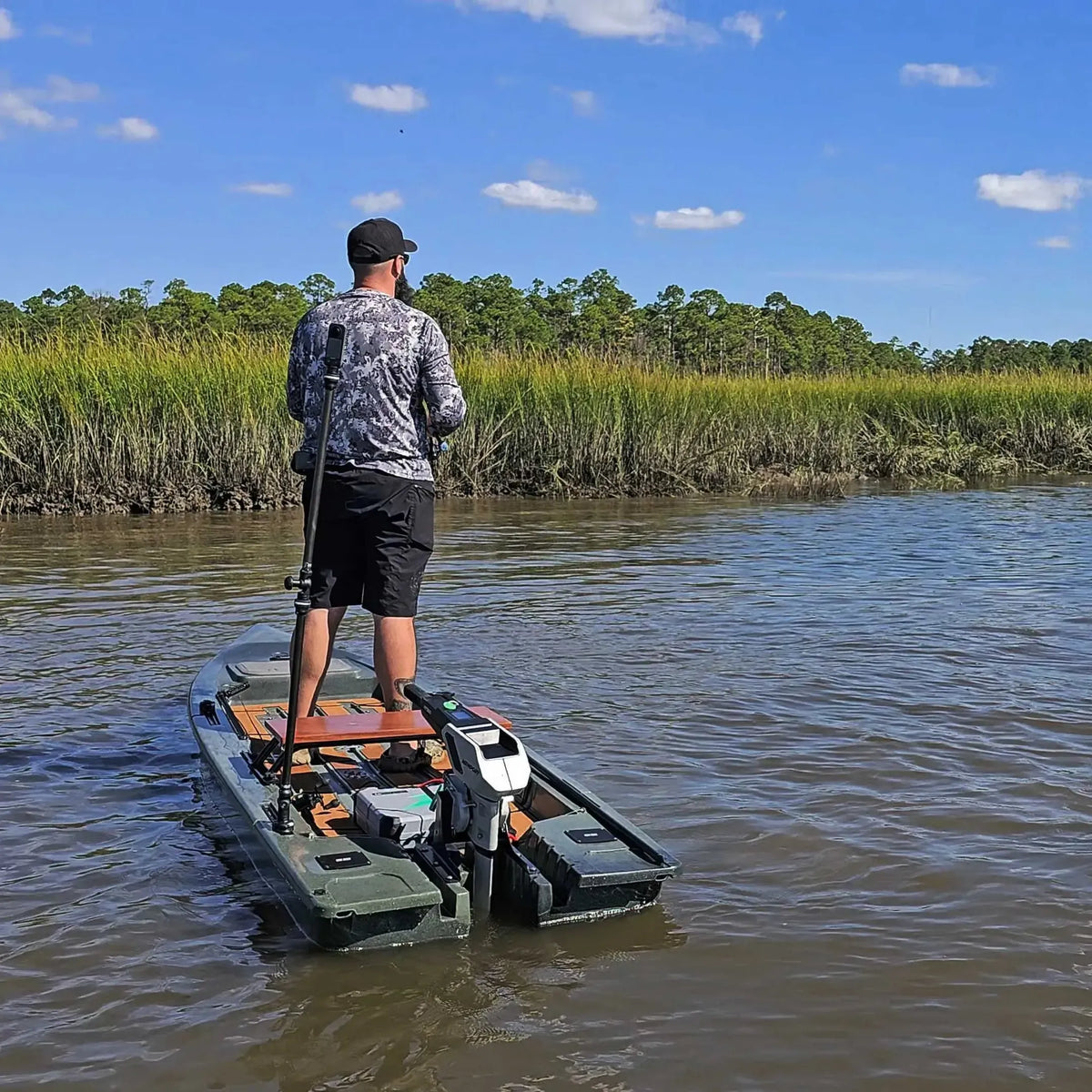 Angler standing in an olive Crescent Cres-Craft fishing skiff with a motor, on a calm river.