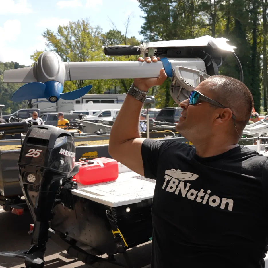 A man wearing a black shirt poses next to the EPropulsion Spirit 1.0 Plus 3HP electric outboard motor. 