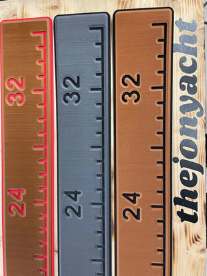 Three textured foam fish ruler pads: brown with pink trim, gray, and brown with black trim, showing measurements 24-32.