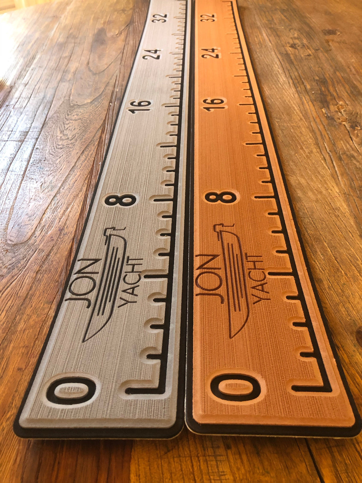 Two 38 1/4" x 4" ruler pads, one light gray and one orange, with "JON YACHT" logo and measurements on wood.