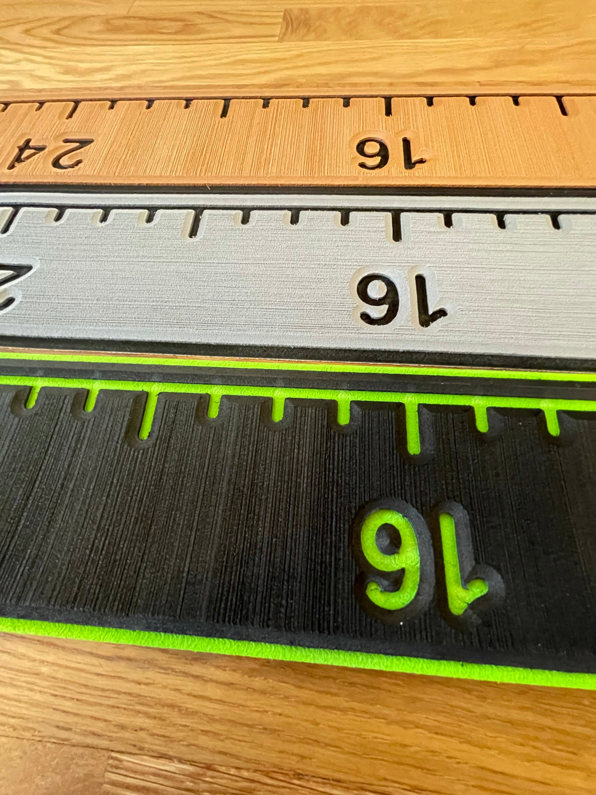 Three fish ruler pads: wood-grain, silver, and black with neon green numbers, showing measurements.