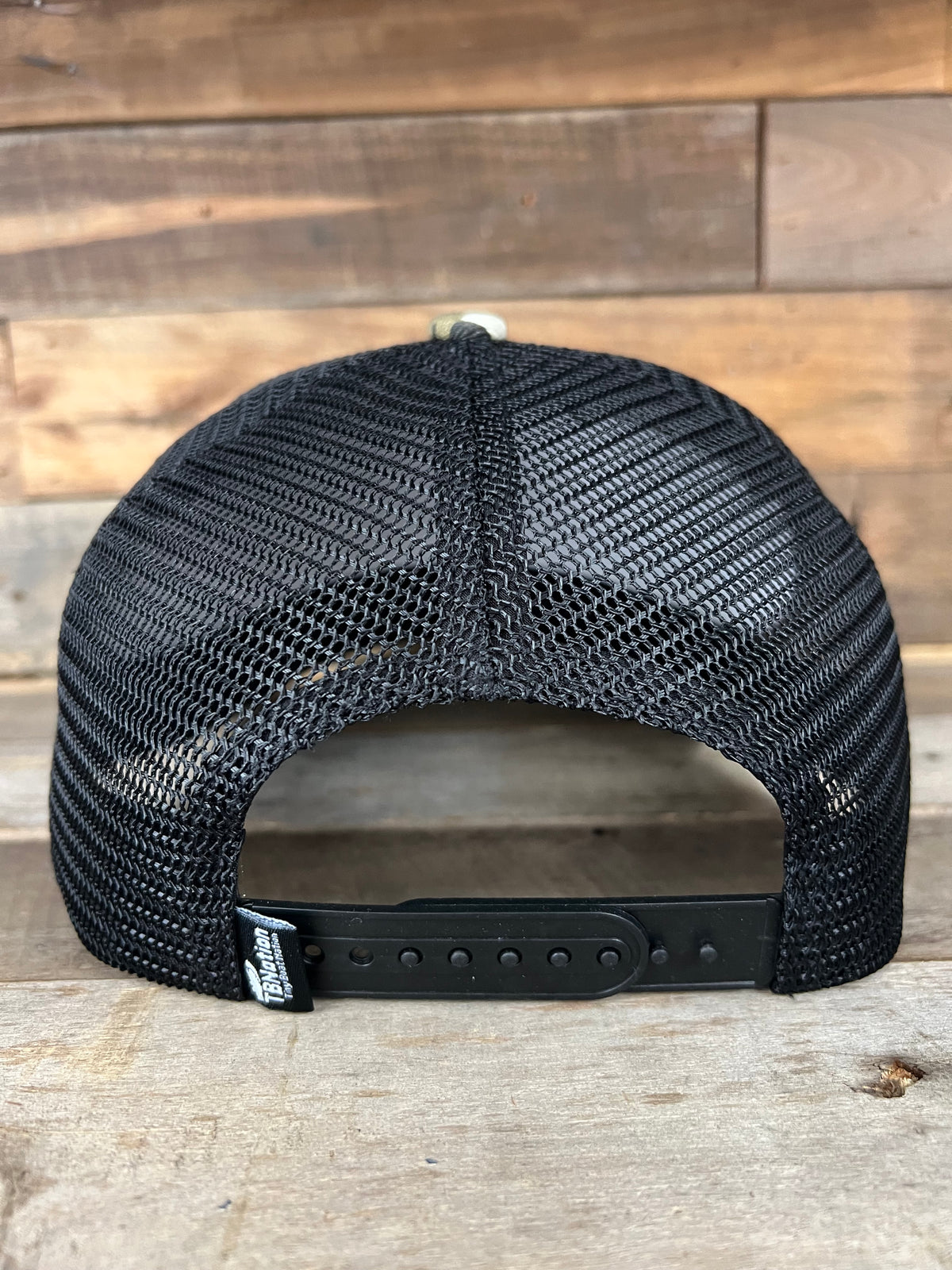 Black mesh trucker hat with adjustable snapback closure and small "Tiny Boat Nation" tag.