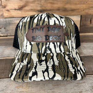 Camo trucker hat with black mesh back and a brown leather patch reading "Tiny Boat Big Deck.